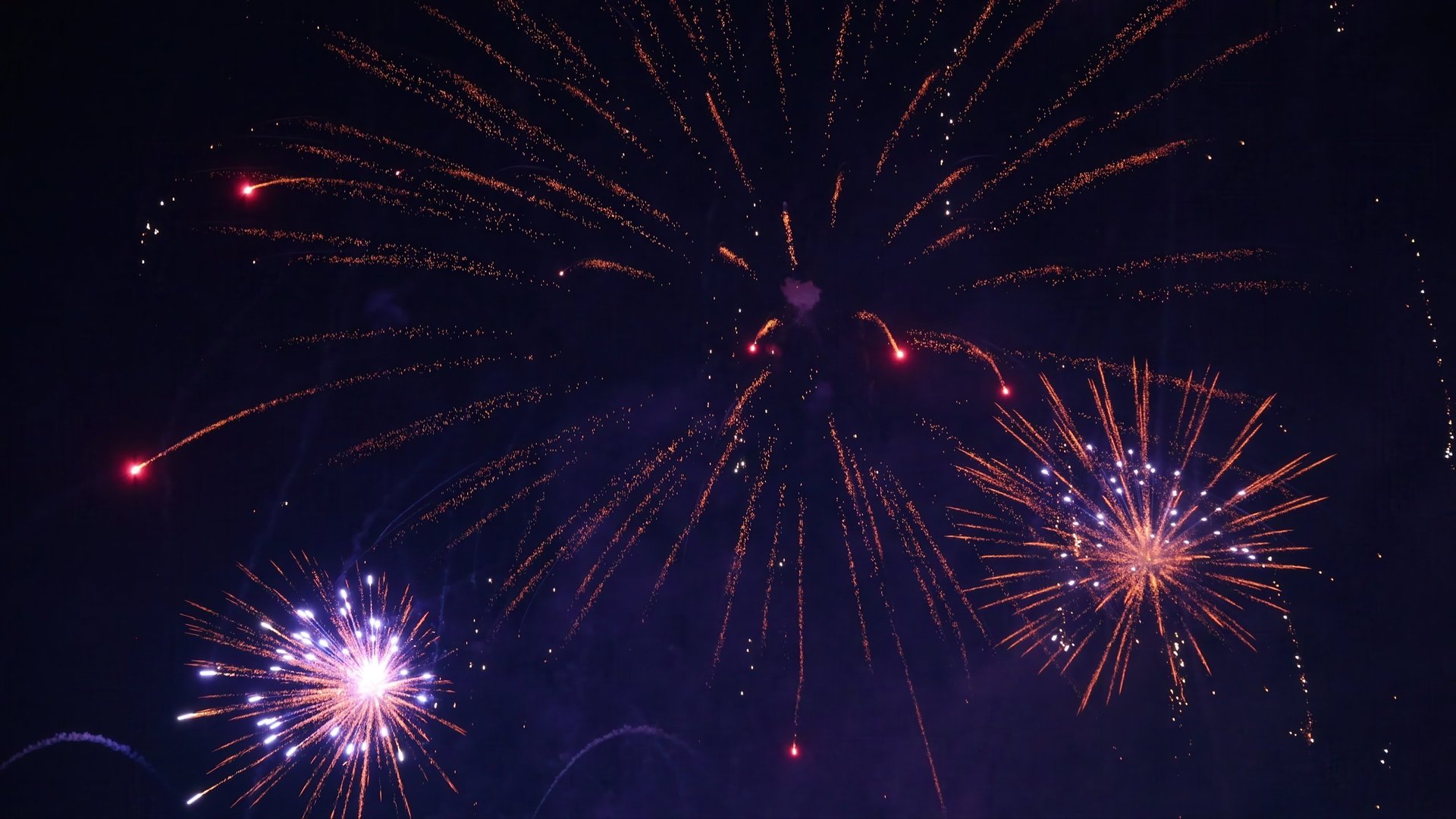 Bright and colorful fireworks bursting into vibrant displays against the dark night sky, creating a festive atmosphere for New Year's Eve celebrations