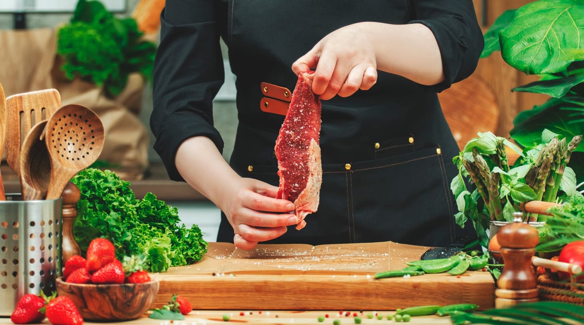 Woman chef skillfully cooks with fresh herbs and vegetables in a warm kitchen