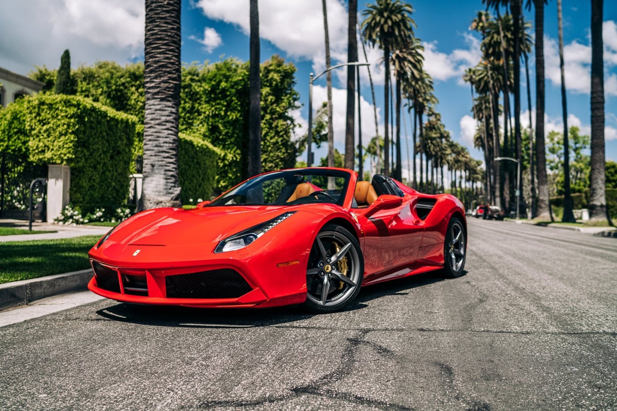 Ferrari 488 parked showing the front of the car with palm trees in the background