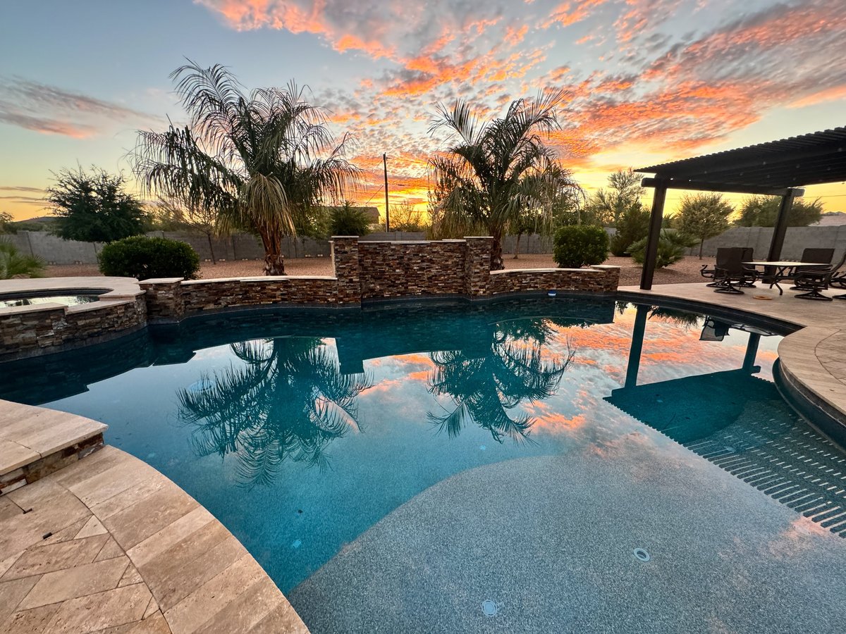 Beautiful desert sunset in an Arizona backyard with a palm tree and swimming pool