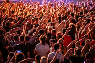 Fans raising their hands and dancing joyfully, celebrating live music at a vibrant music festival filled with excitement and energy