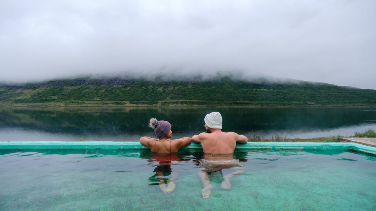 Couple relaxing in geothermal hot spring surrounded by Icelandic nature