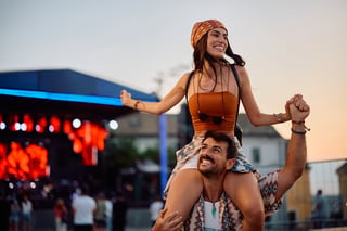 Happy man carrying his girlfriend on shoulders during summer music festival