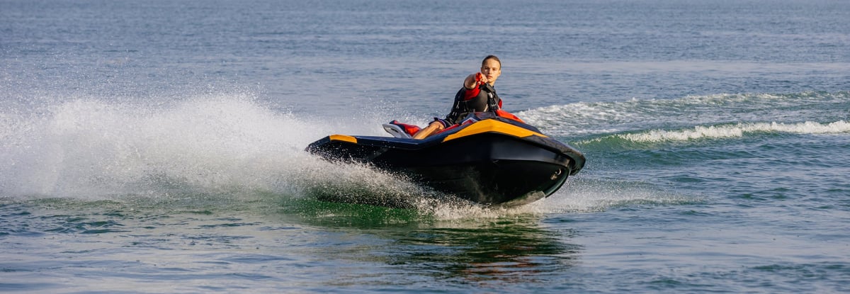 Young man speeds on a jet ski under the bright summer sun