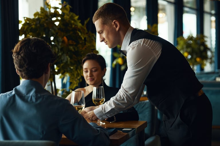 Caucasian young adult man serving wine at restaurant table