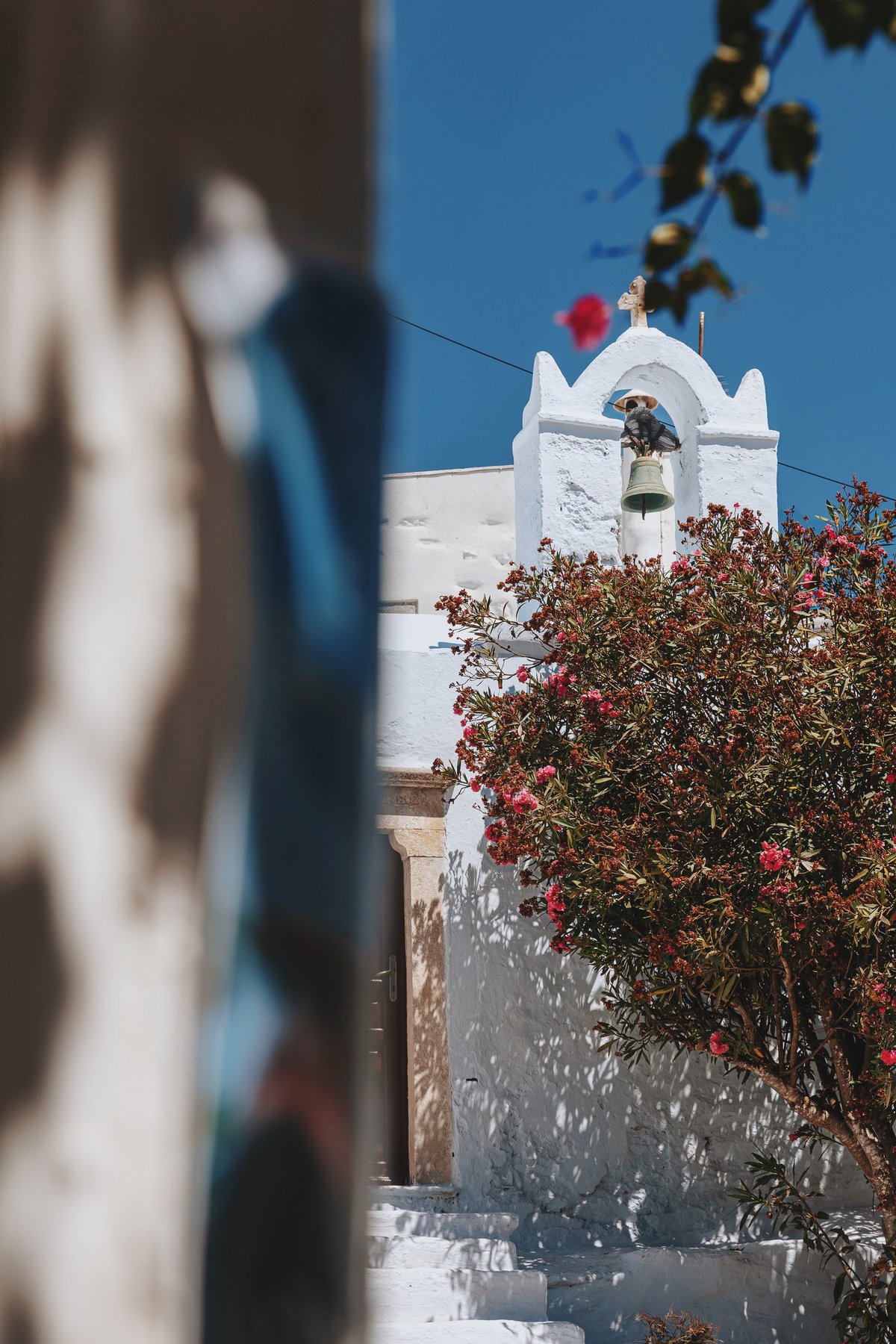 A quiet moment in a Cycladic village with whitewashed church and vibrant flowers