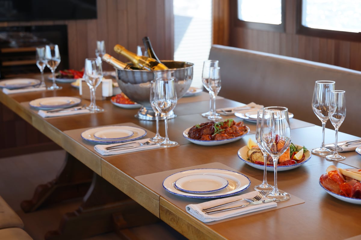 A lavishly decorated dining table with gourmet dishes and champagne in a stunning yacht setting