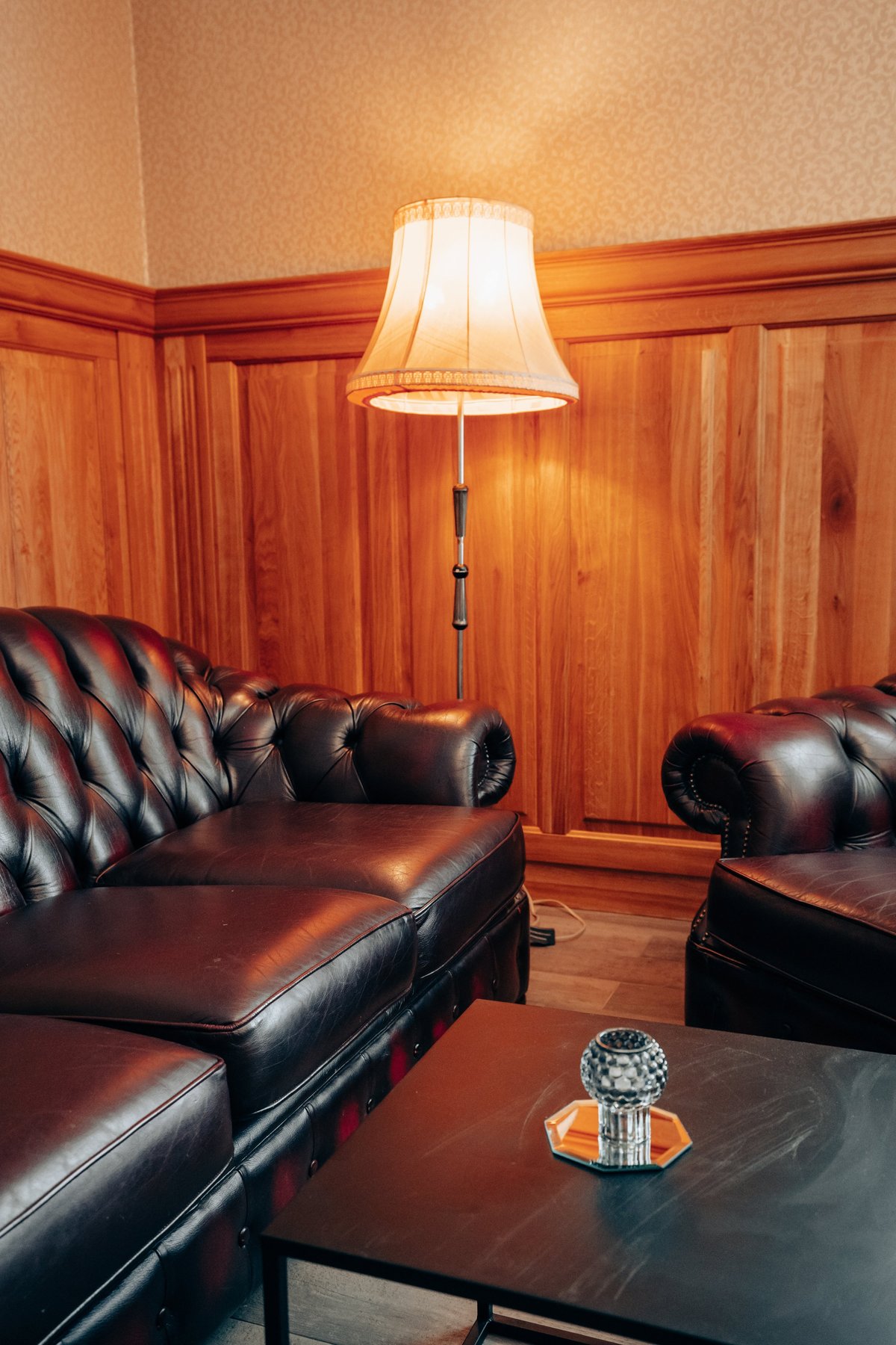 A sophisticated lounge corner with dark brown leather Chesterfield sofas