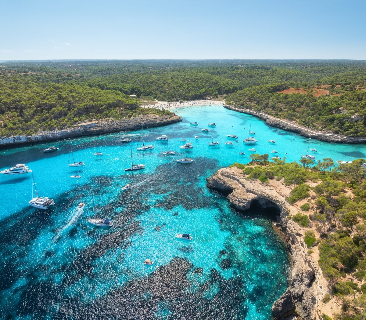 Aerial drone view of yachts and boats anchored in turquoise bay near Mallorca