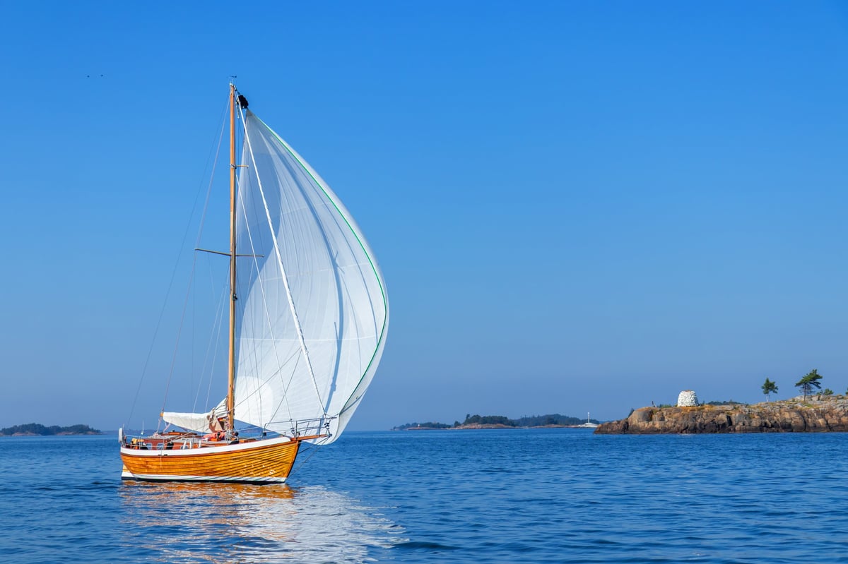 Wooden yacht sailing in regatta race with spinnaker sail