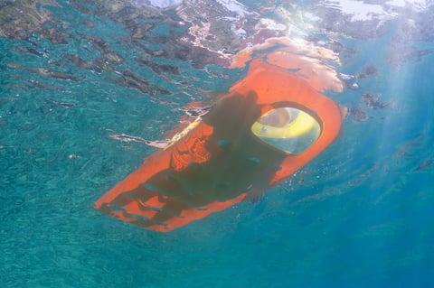 Girl on inflatable raft viewing porthole underwater