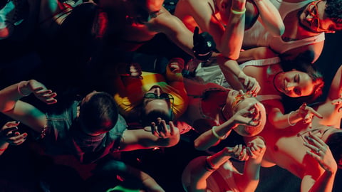 Aerial view of vibrant crowd dancing under colorful lights at a lively nightclub party celebration