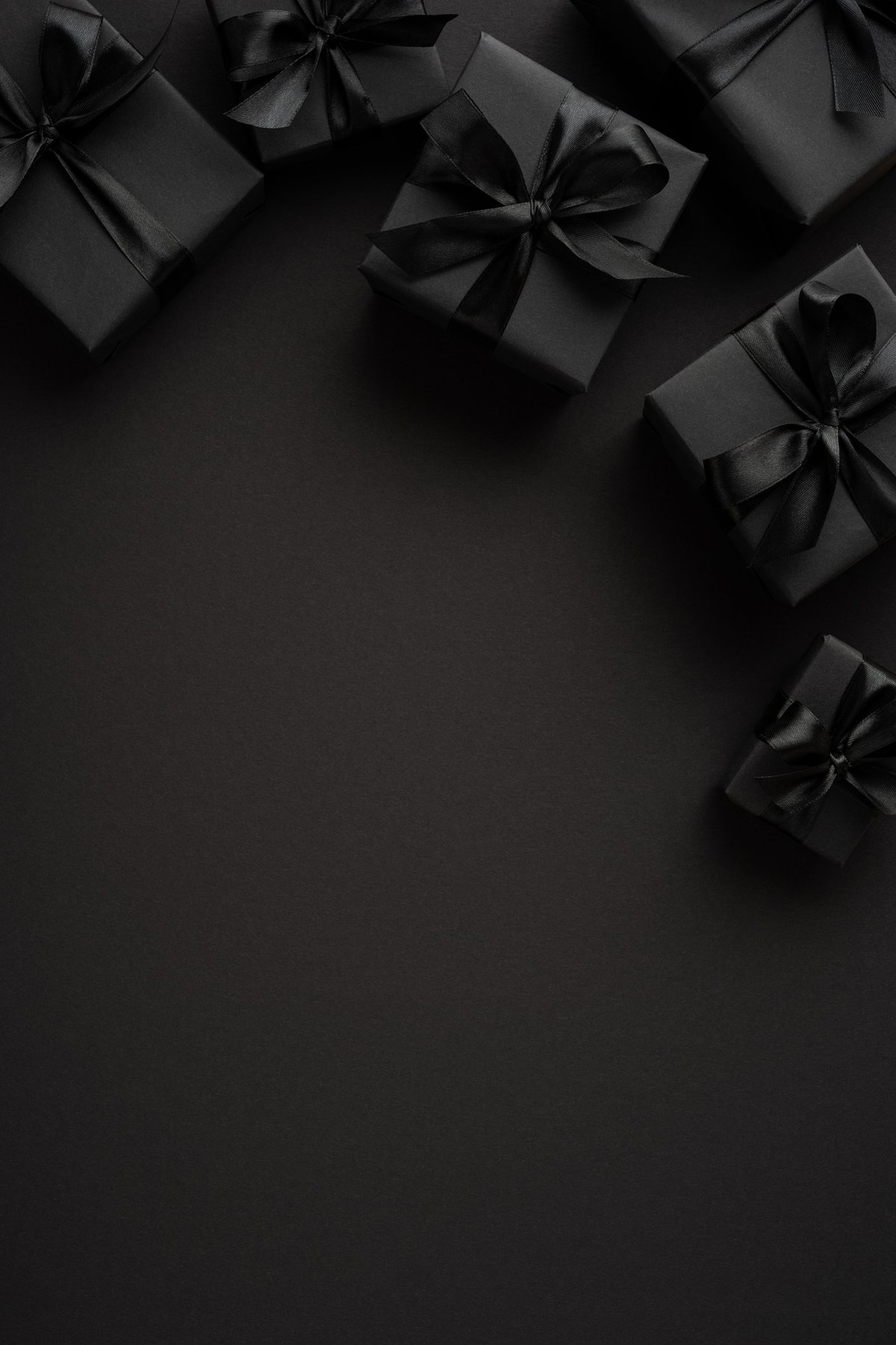 Elegant black-wrapped gifts with matching ribbons on a dark surface for luxury celebrations