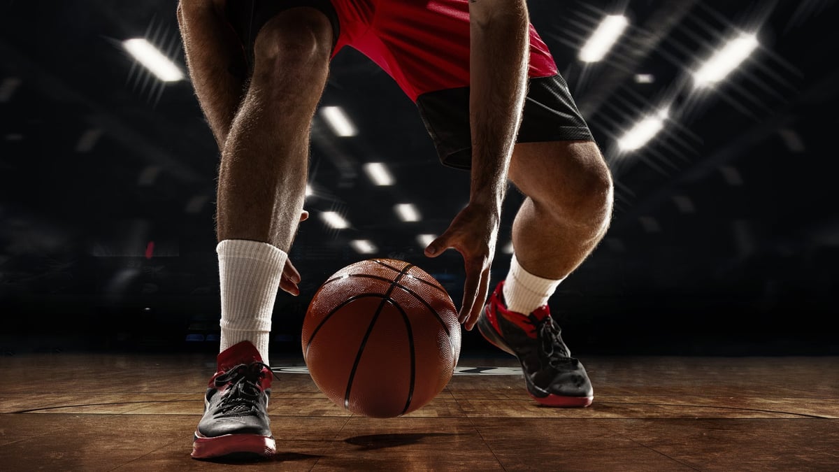 Basketball player dribbling on hardwood court, low angle action shot