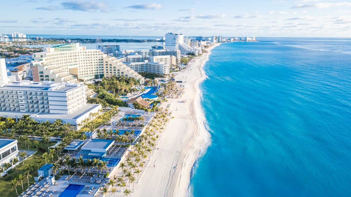 A beautiful beach with a blue ocean and a few buildings in the background