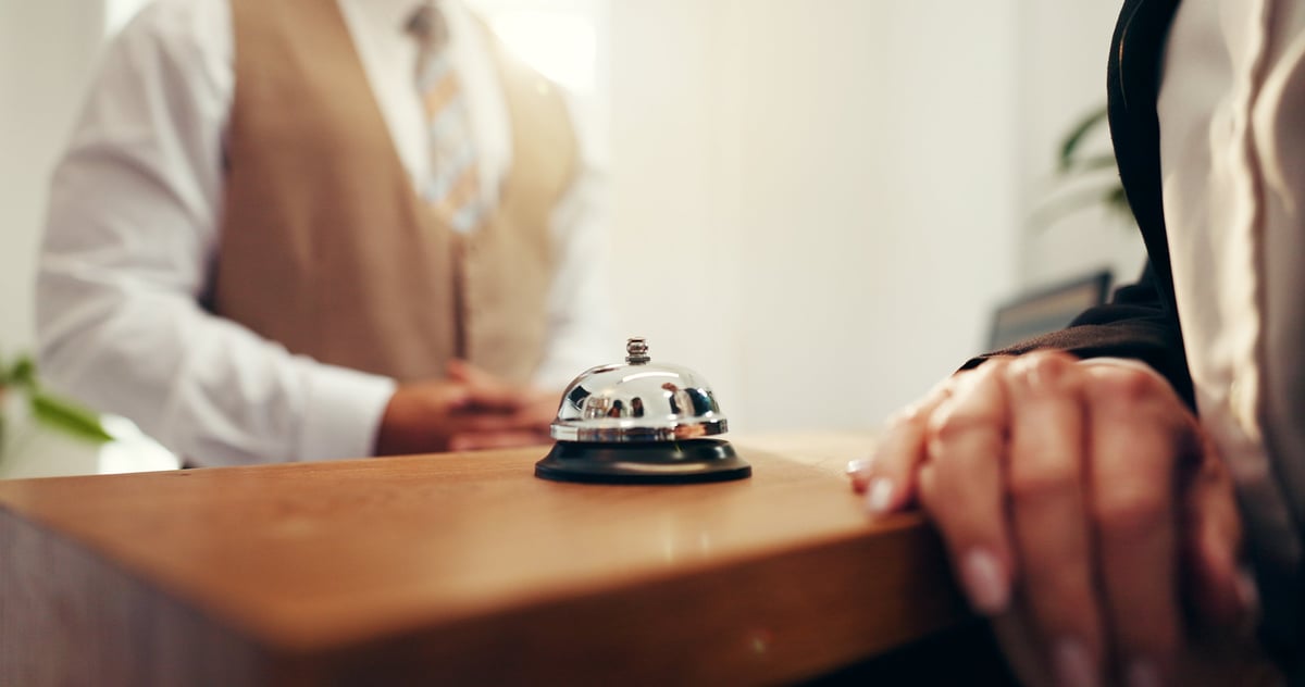 Customer hands and concierge with service bell for request assistance at hotel