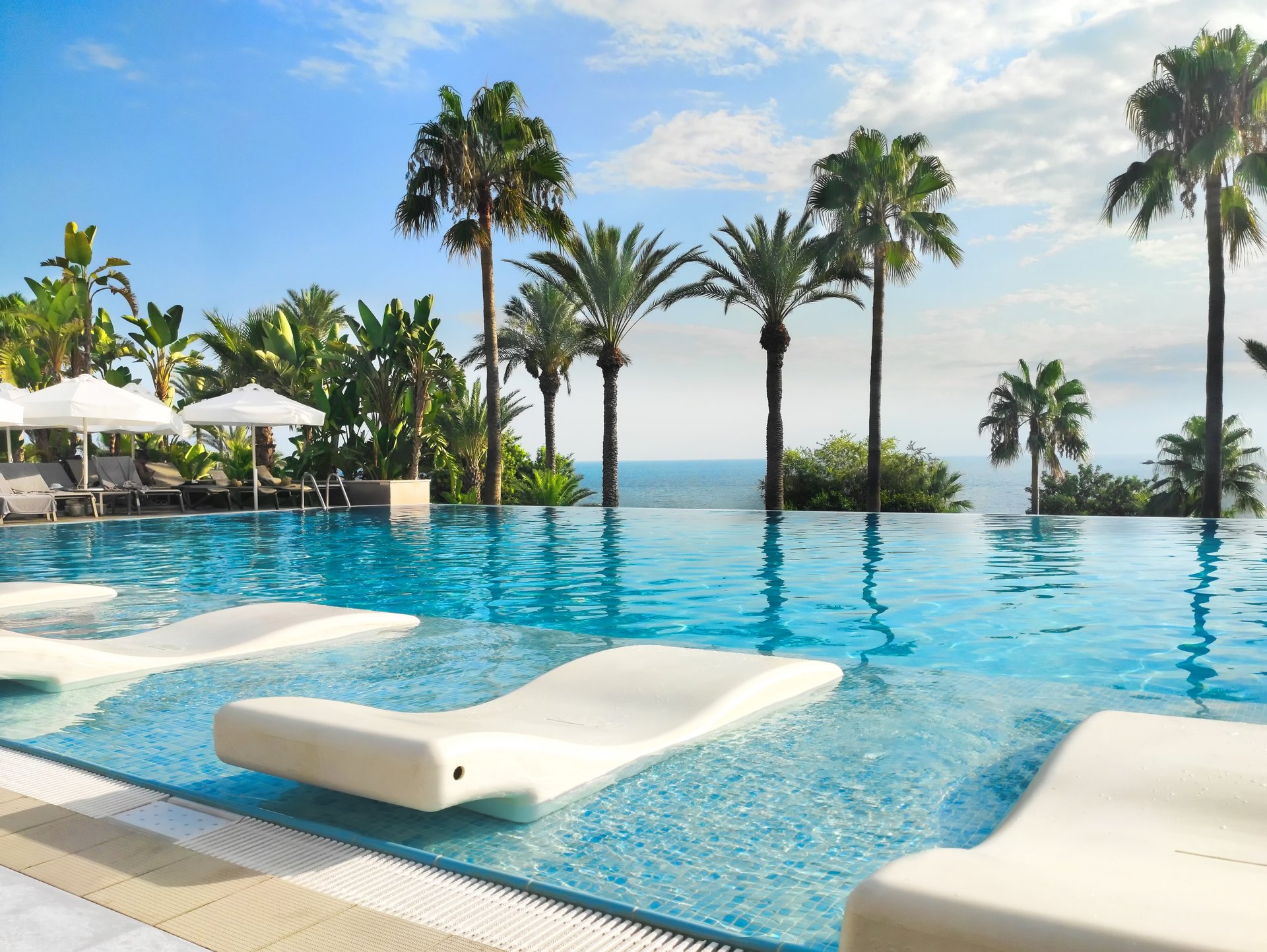 Stunning luxury resort pool with loungers, palms, and ocean views in Mauritius