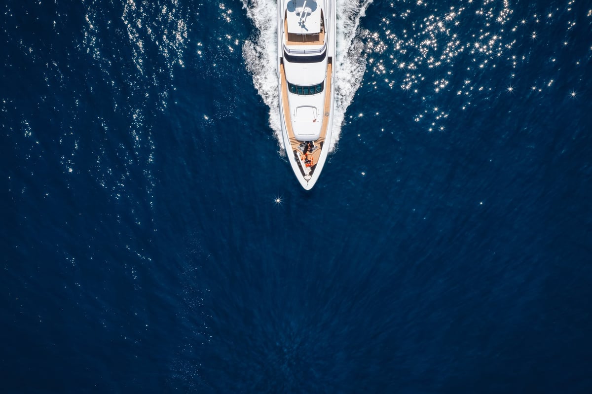 Aerial overhead view of a bow of a luxury yacht cruising with speed over ocean