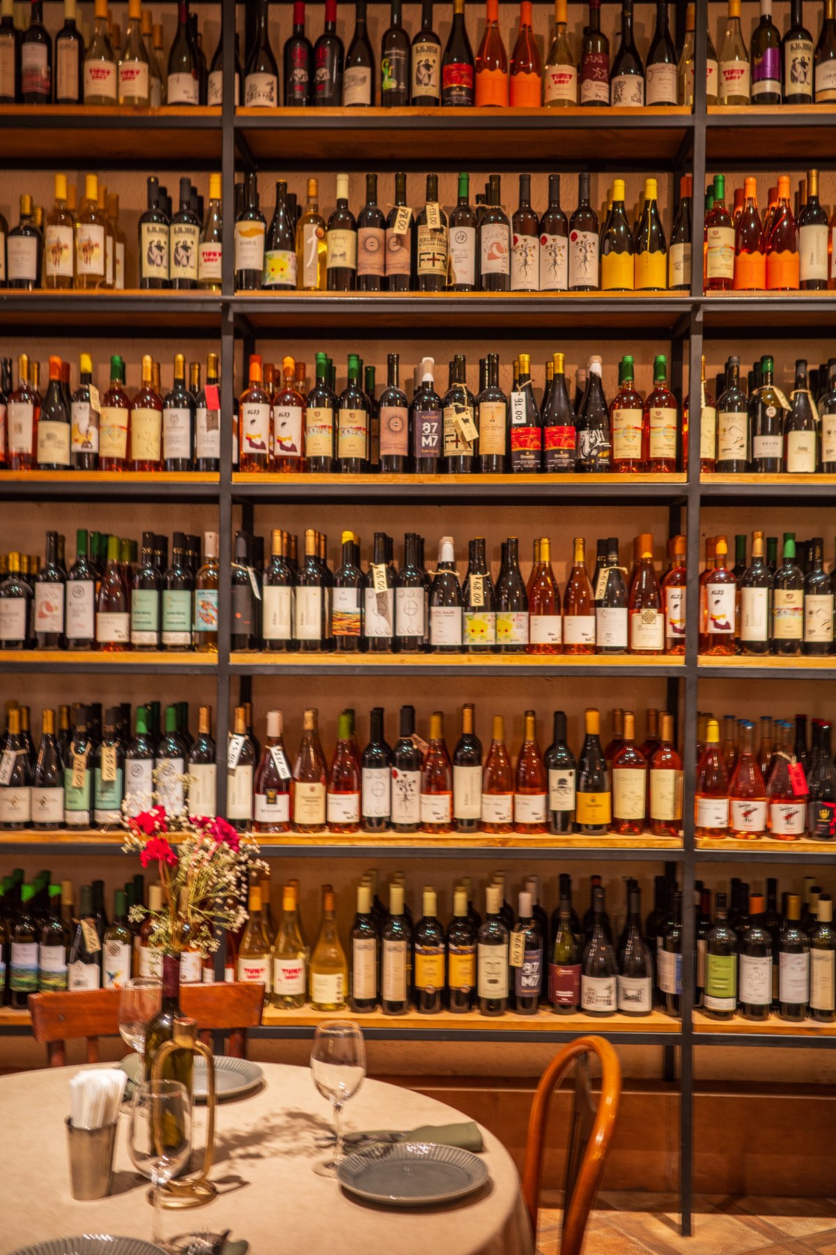 A cozy wine bar interior featuring shelves filled with colorful bottles of wine