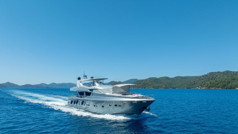 Aerial view of a super yacht gliding through crystal clear waters with a scenic marina nearby