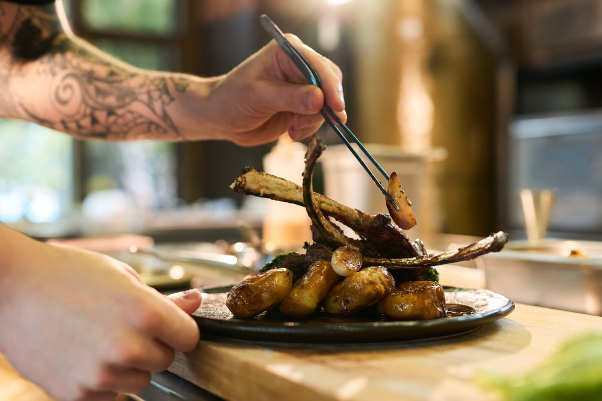 Private chef plating gourmet lamb chops in luxury kitchen