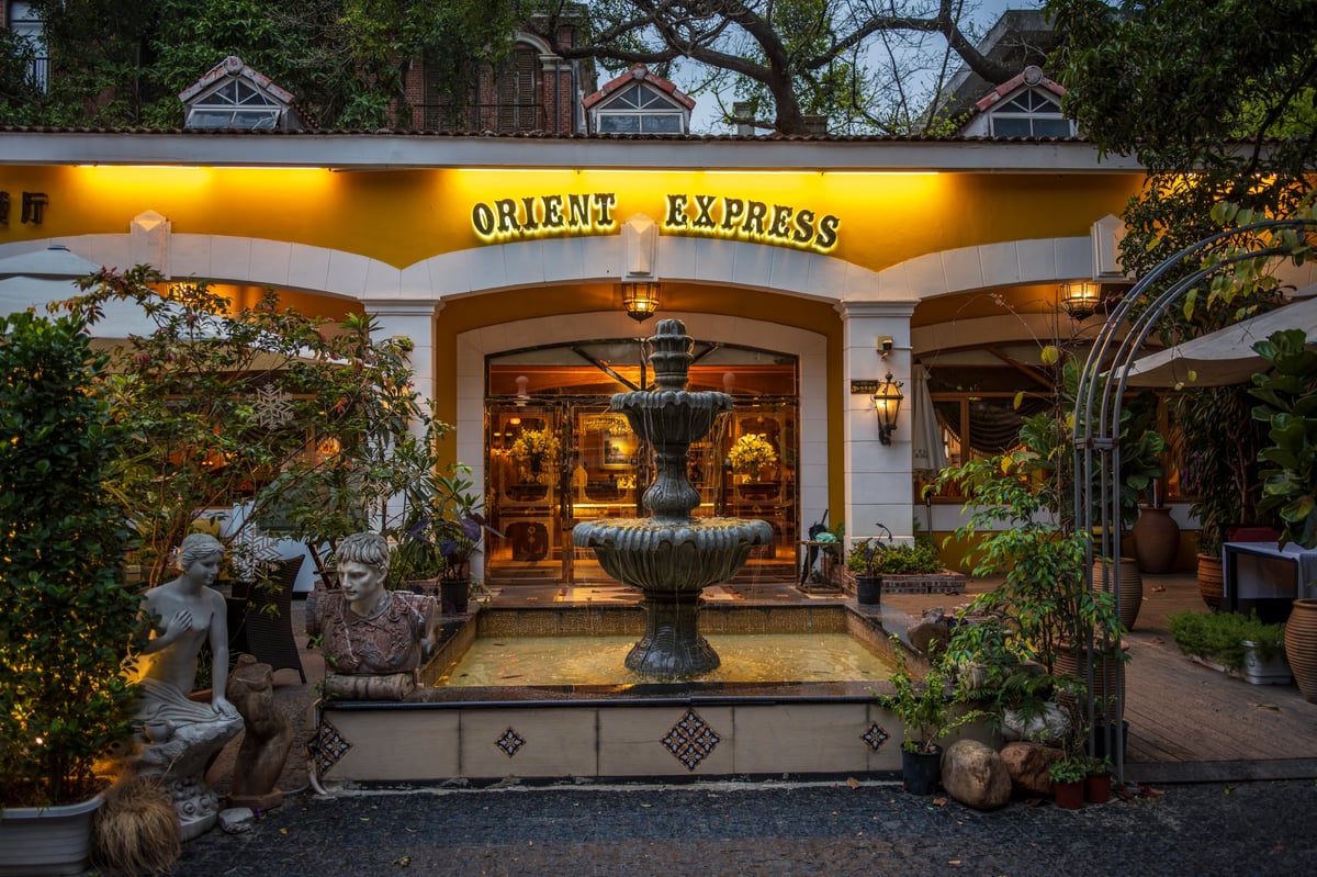 Orient Express themed restaurant with illuminated facade and fountain at evening entrance