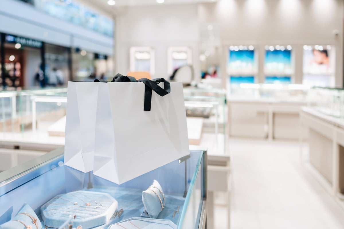 White luxury shopping bags with black ribbon on display case in modern jewelry store