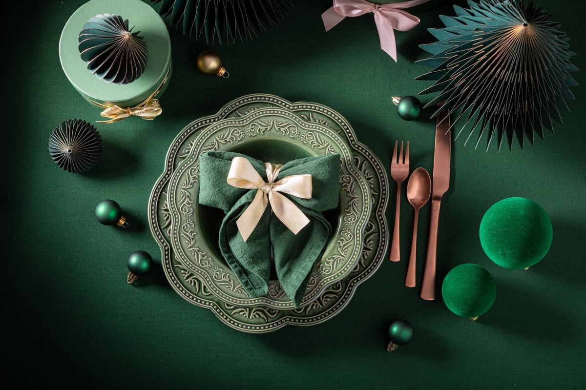 Elegant dark green Christmas tableware with bubbles and gifts in cozy home atmosphere