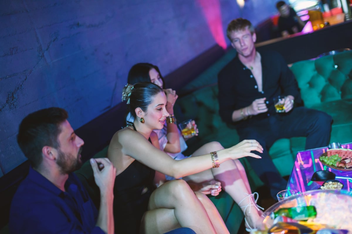 Young group lounging in a nightclub VIP area enjoying drinks and a lively festive atmosphere