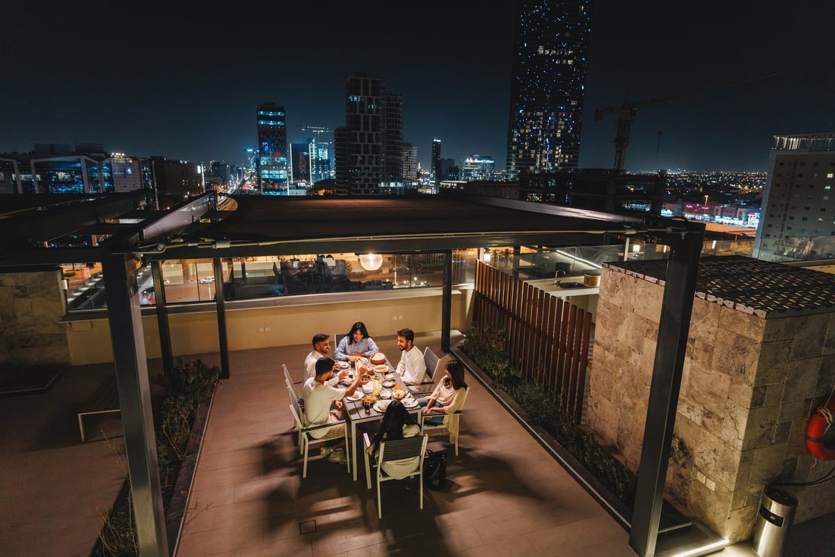 Group of cheerful friends enjoying a festive dinner on a rooftop terrace