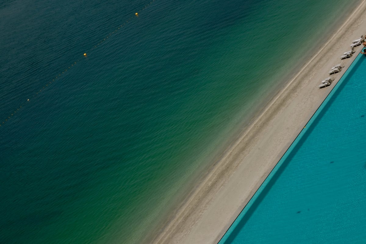 Luxury resort swimming pool beside turquoise ocean waves, tropical vacation concept