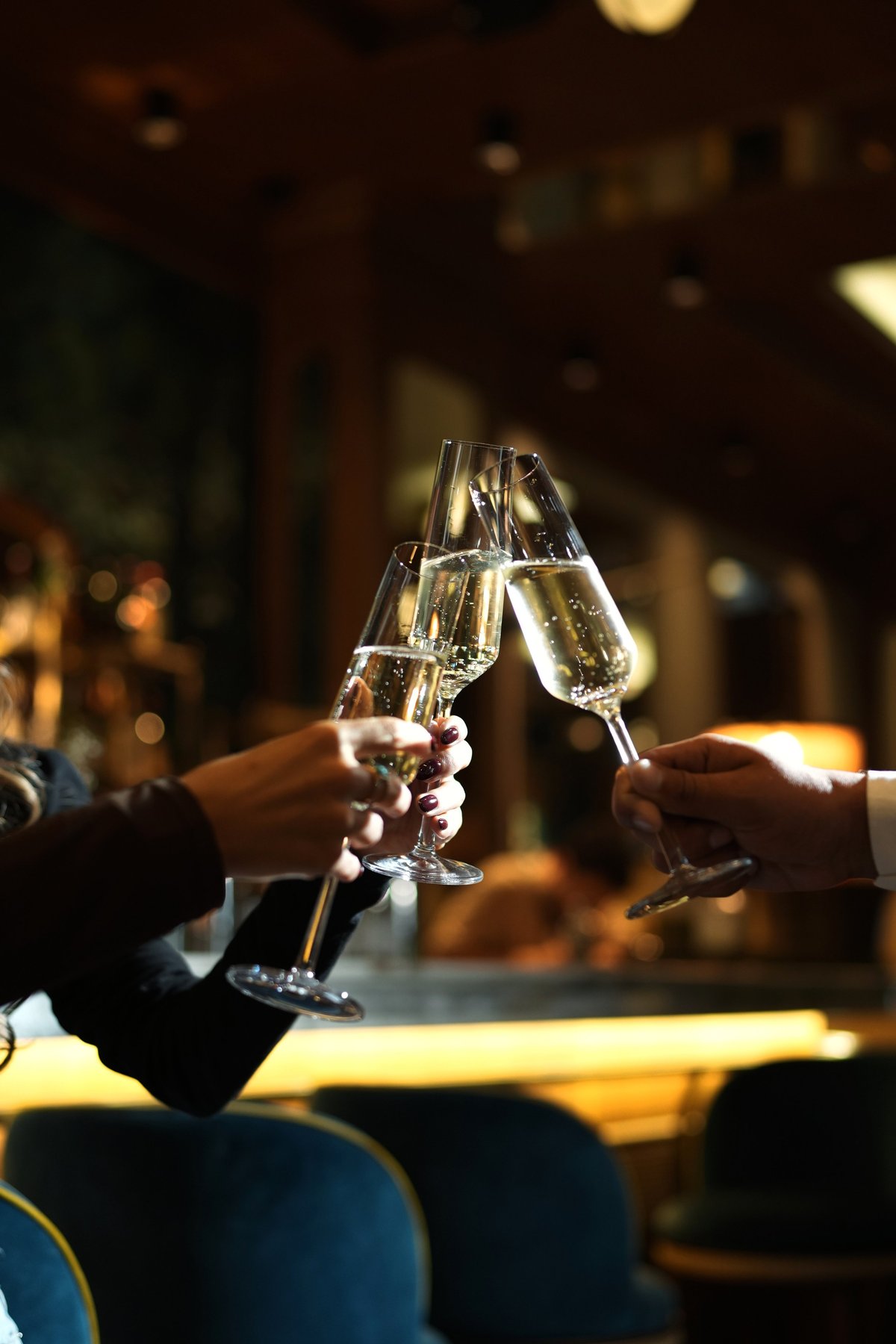 Three hands clinking champagne flutes in celebratory toast