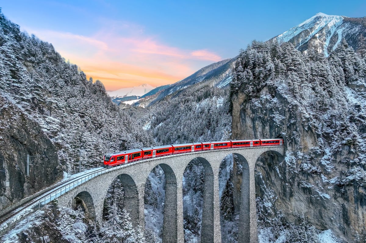 Aerial view of train crossing Landwasser Viaduct through Swiss Alps in winter snow
