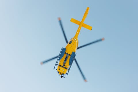 Yellow rescue mountain helicopter flying against clear blue sky