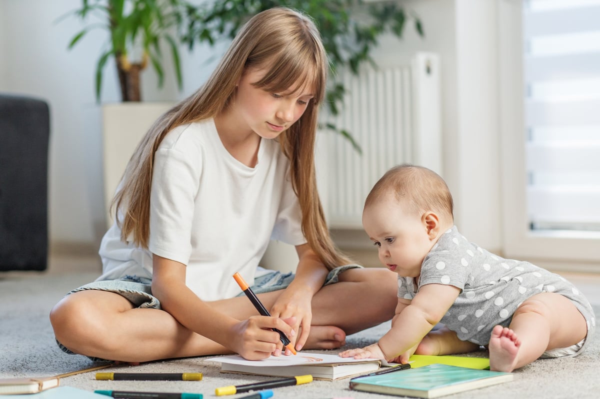 Teen girl and baby sibling spending quality time together drawing
