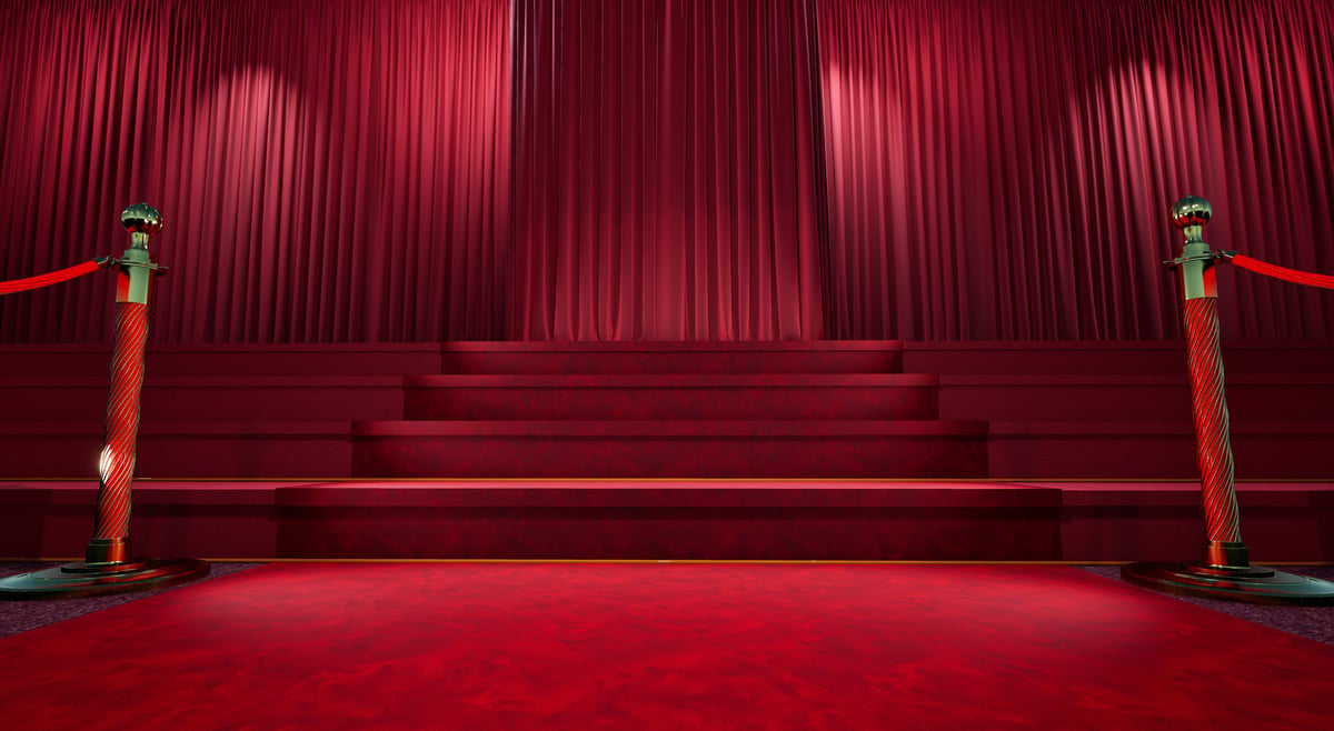 Red carpet with barriers leading to staircase and red curtain at prestigious ceremony venue