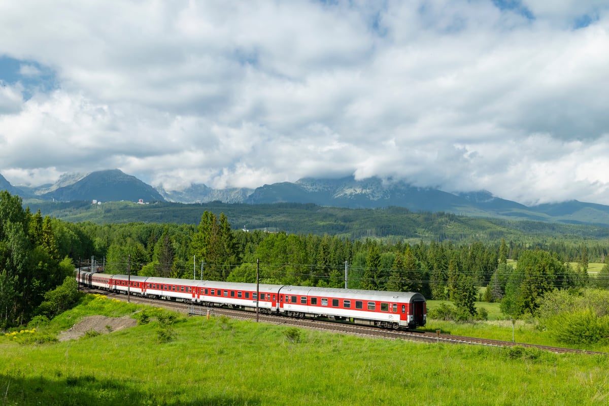 Train moving through green mountain landscape