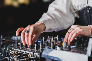 DJ adjusting knobs on professional mixer in dark club