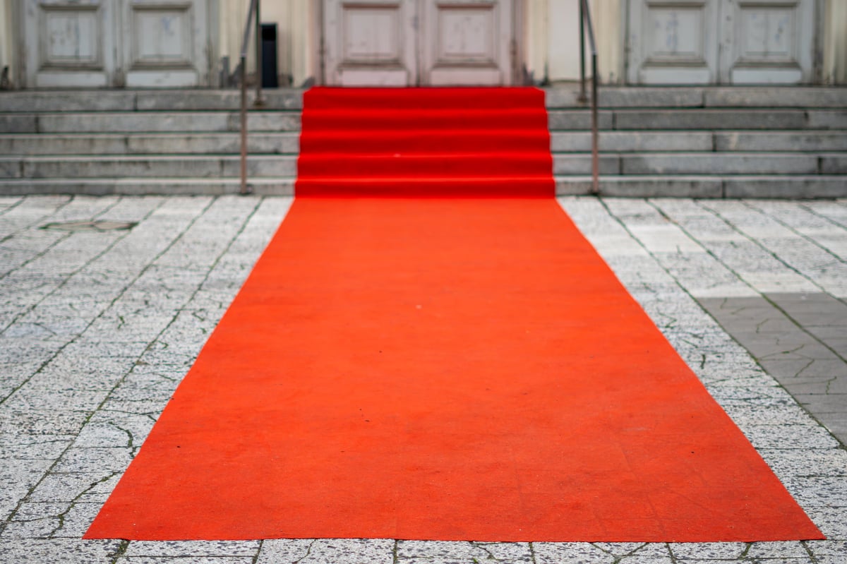 Red carpet leading across stone tiles toward the stairs and historic building doors prepared for a formal ceremonial event