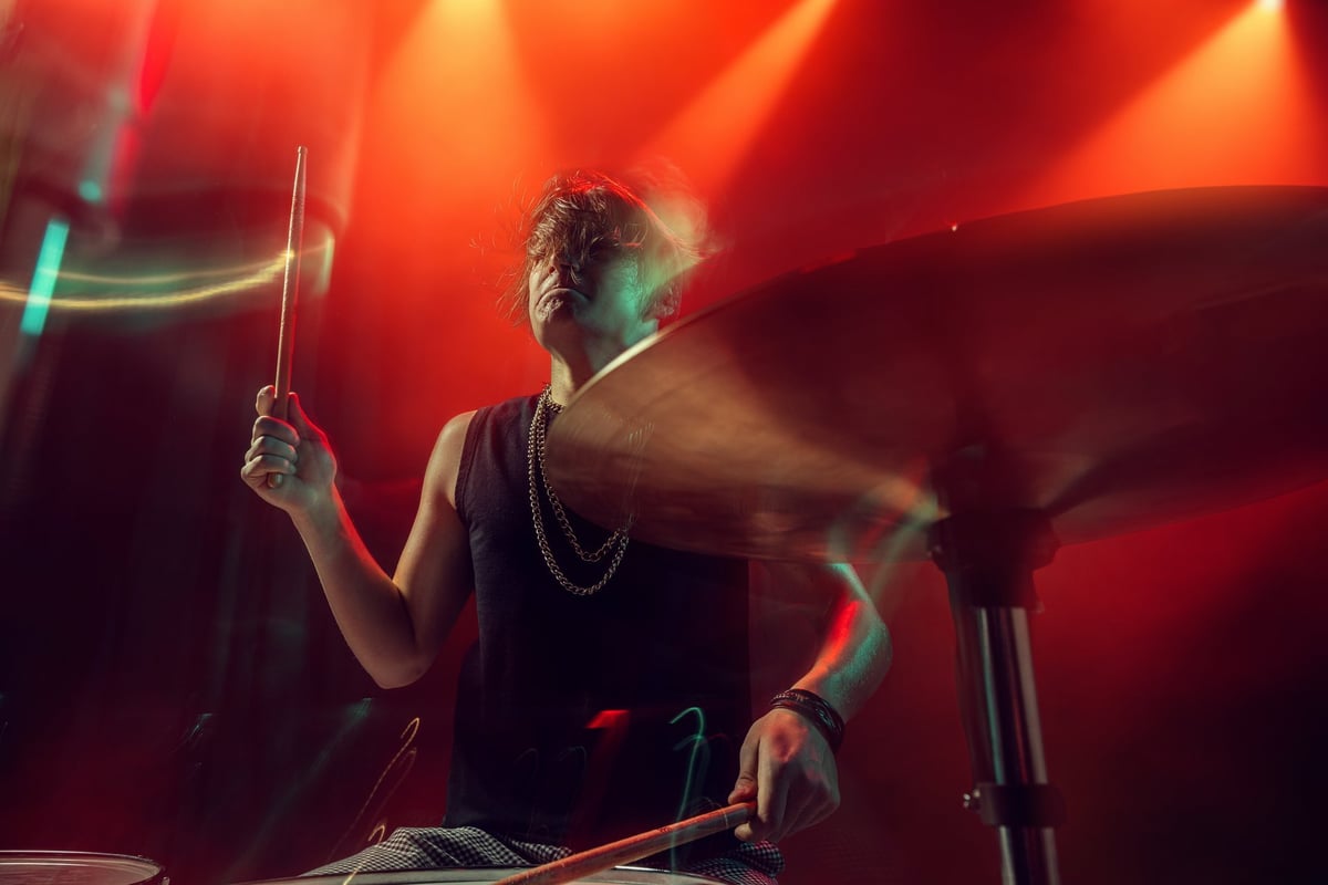 Drummer under red light playing with intense emotion and motion blur streaks