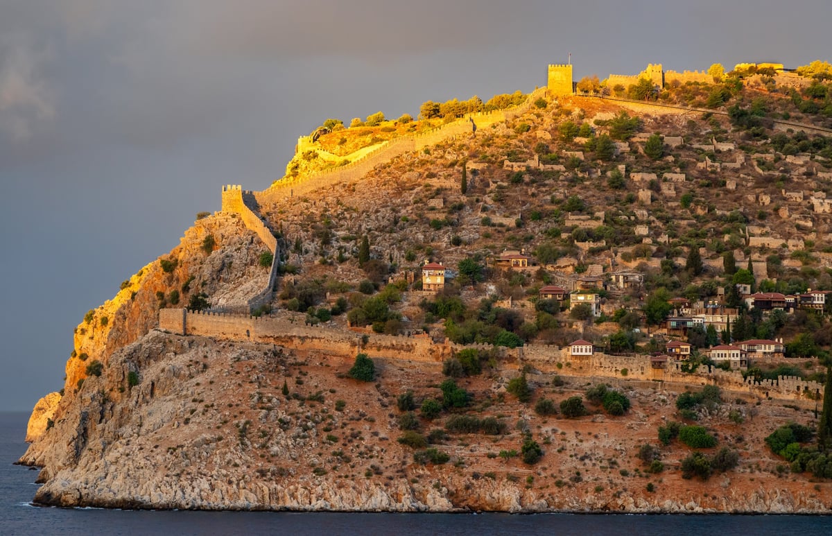 Golden sunset light illuminates Alanya Castle above the Mediterranean Sea in Alanya Turkey
