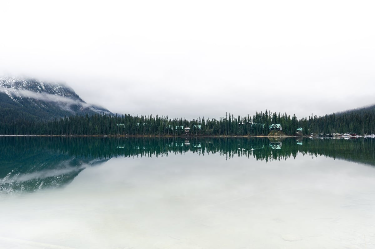 A serene lakeside view with forest and mountain reflecting on calm water