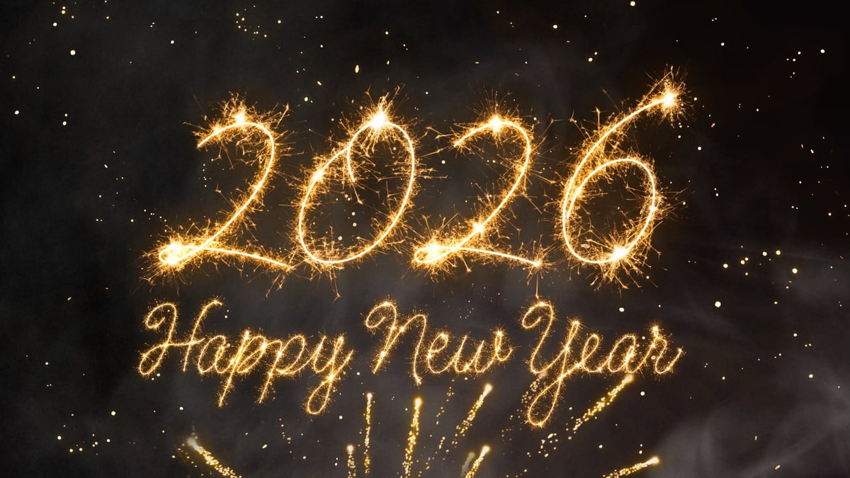 Dazzling golden light tracing Happy New Year against a deep blue night sky with glowing particles