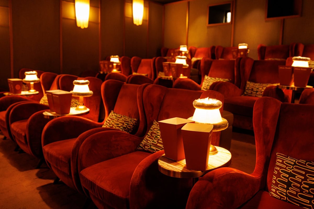 Warm interior of an empty boutique cinema with red armchairs and small tables