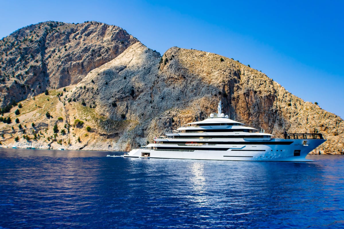 Luxury yacht cruising the turquoise Mediterranean Sea near the Italian coast with Capri-style rocky coastline