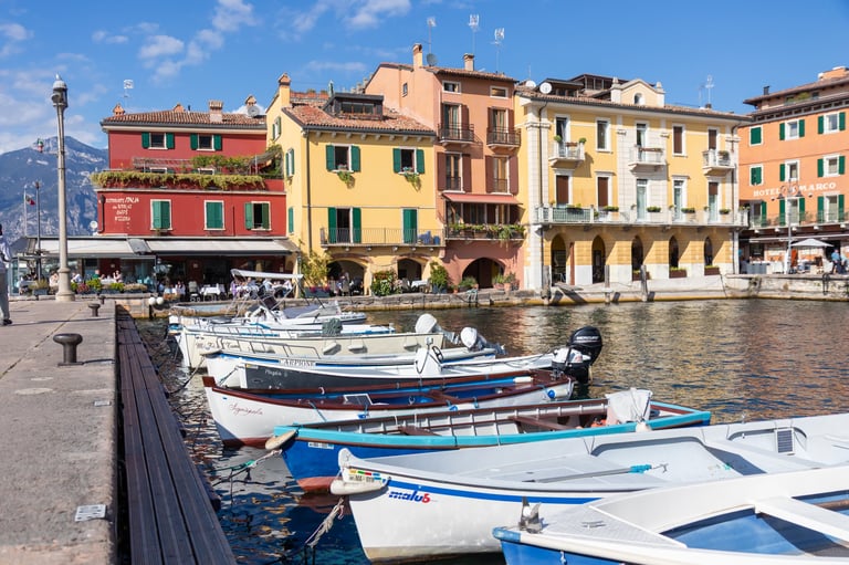 Picturesque harbor of Malcesine on Lake Garda, Italy, featuring calm water, boats, and charming lakeside town