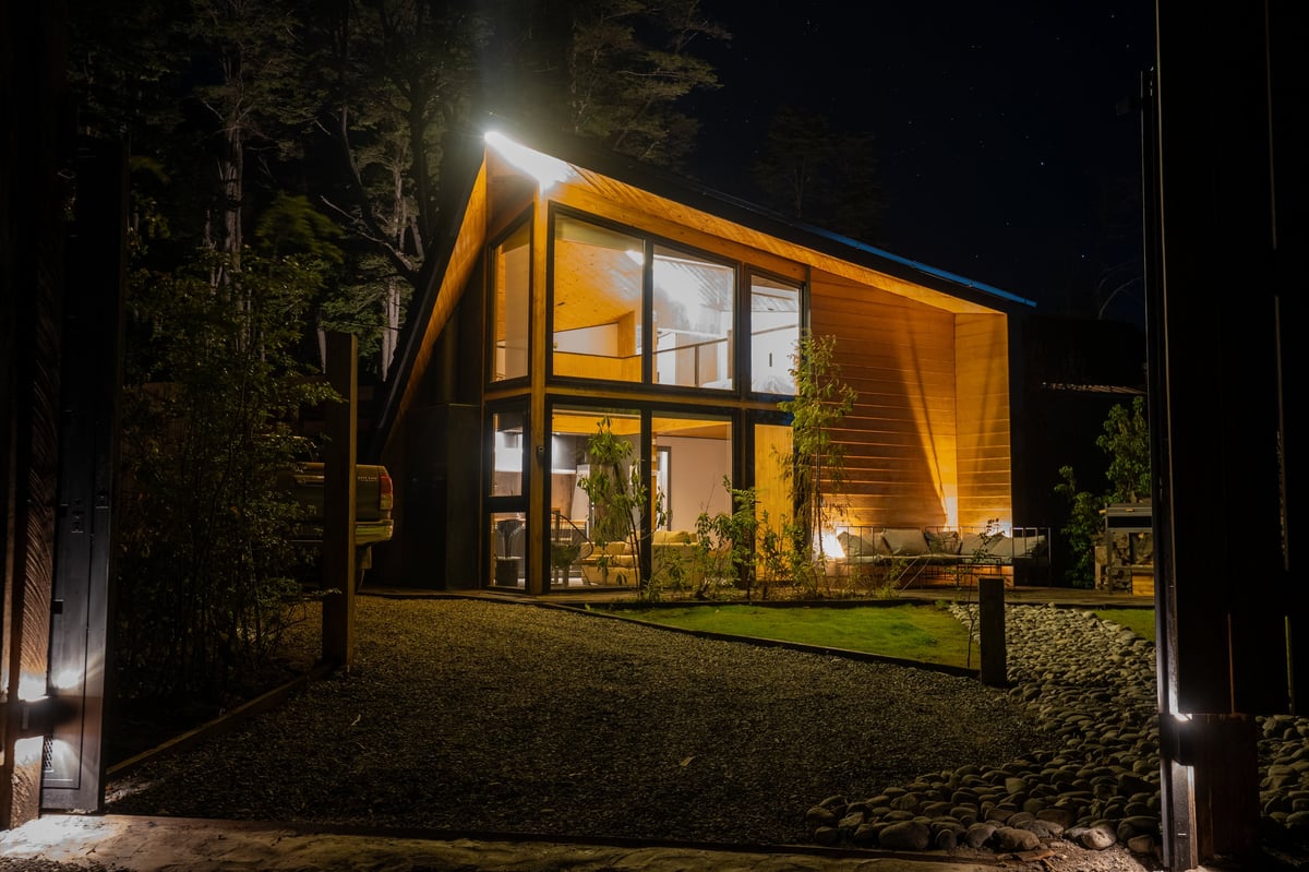 Modern mountain home warmly illuminated at night in forest setting