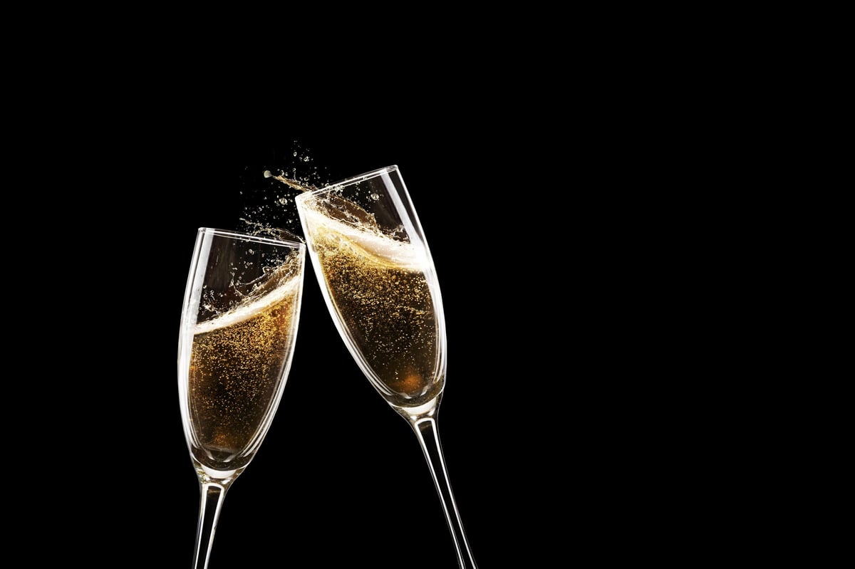 Two champagne flutes clinking in festive toast with golden bubbles