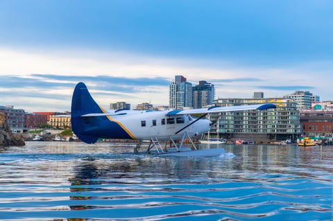 Seaplane landing in harbor with city skyline and summer evening light