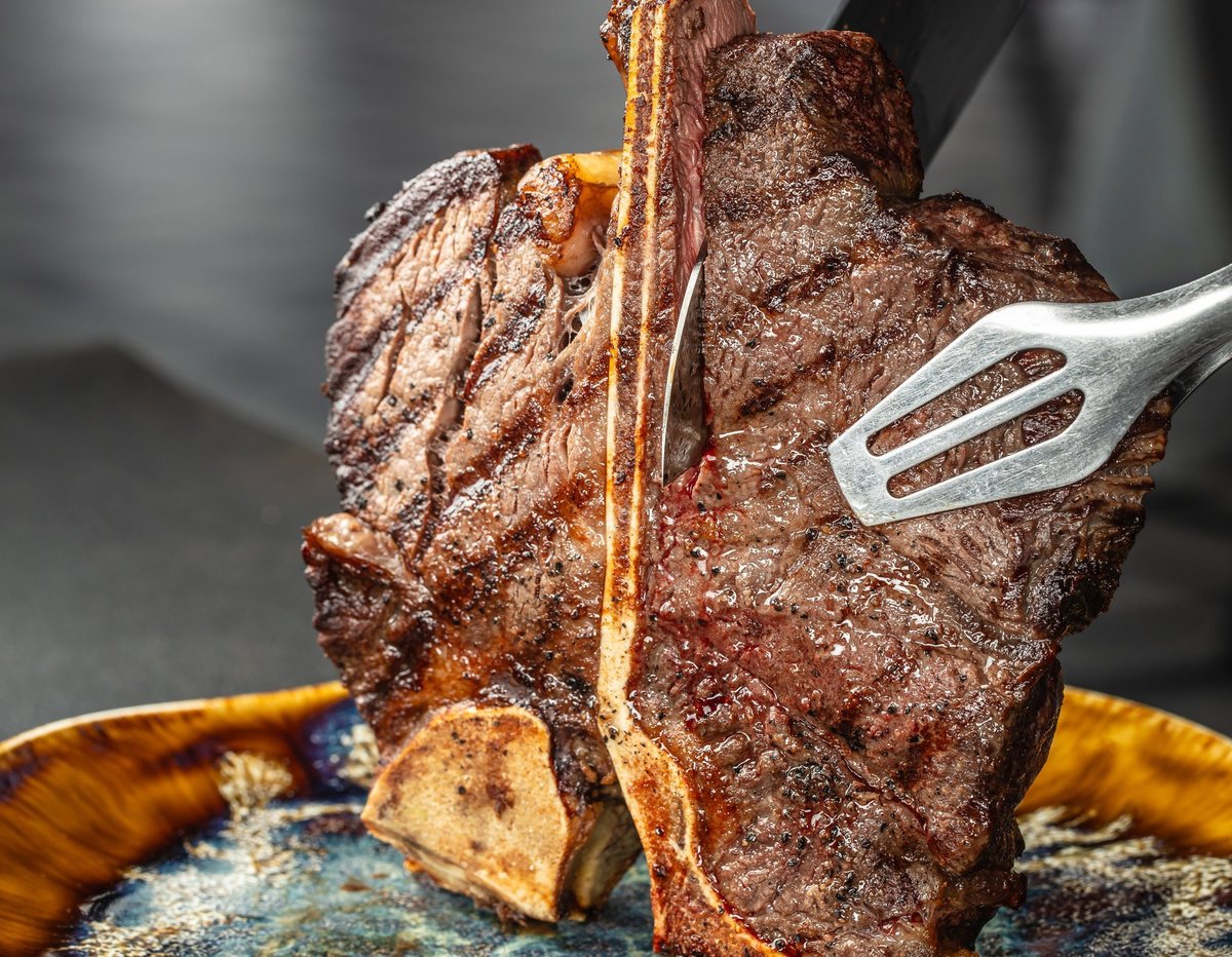 Close-up of juicy grilled tomahawk steak being sliced
